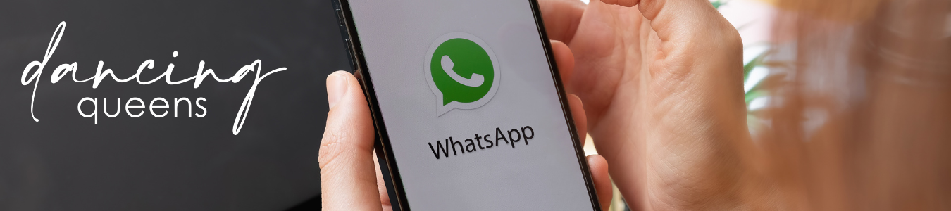 Person hält ein Telefon mit dem WhatsApp-Logo auf dem Bildschirm und dem Text „Dancing Queens“ an der Seite.