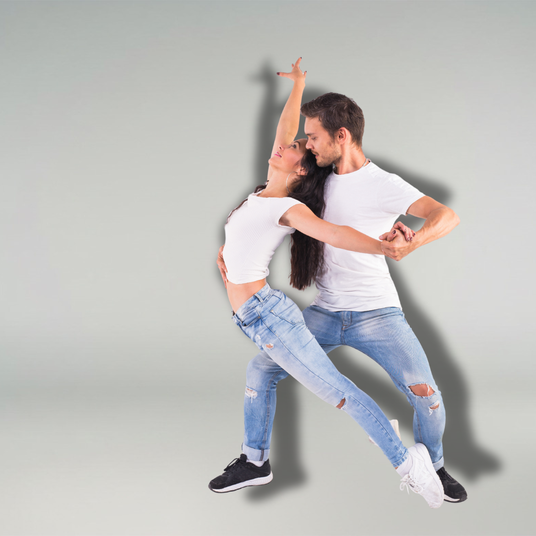 Ein Mann und eine Frau in weißen Hemden und Jeans tanzen zusammen vor einem schlichten hellen Hintergrund.