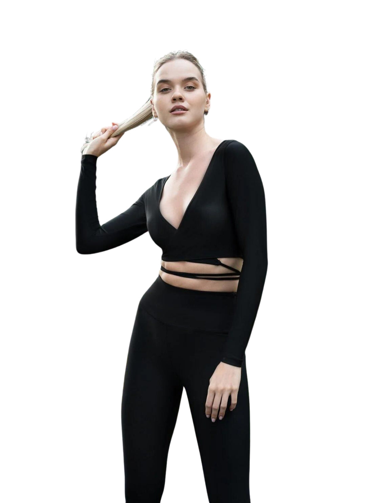 Person in Lisminas 065 Langarm-Top und Leggings, die mit einem Pferdeschwanz vor einem weißen Hintergrund Yoga macht.