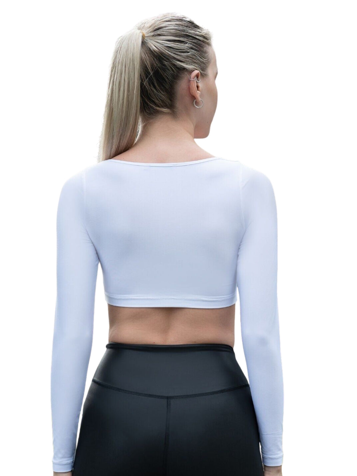 Person mit hohem Pferdeschwanz, die nach außen blickt und Lisminas 081 Ruffled Langarm Shirt in Weiss und schwarze Leggings trägt.