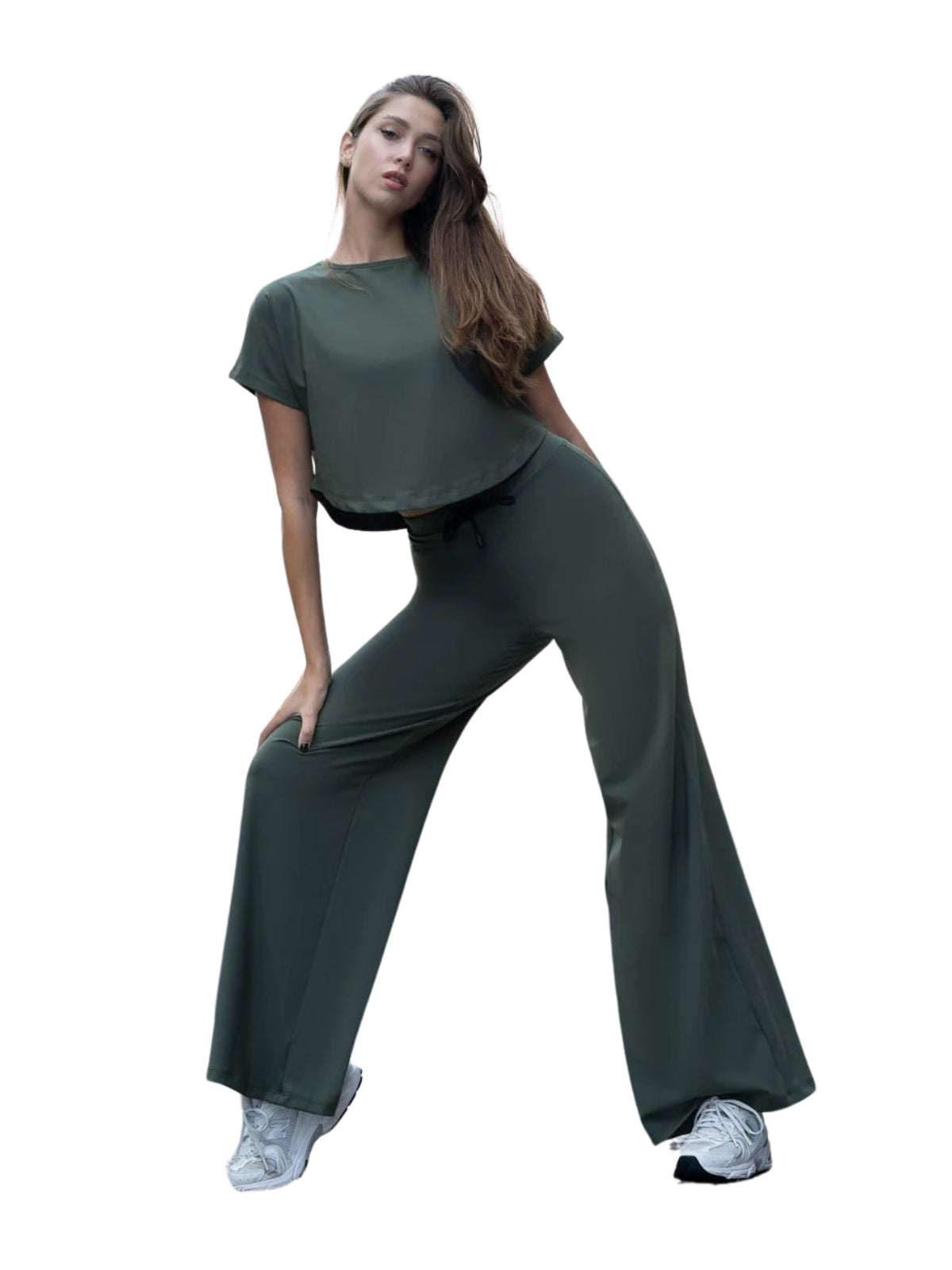 In einer entspannten Yoga-Pose trägt das Model Lisminas khakifarbenes 098 Yoga-T-Shirt mit weißen Turnschuhen vor einem weißen Hintergrund.