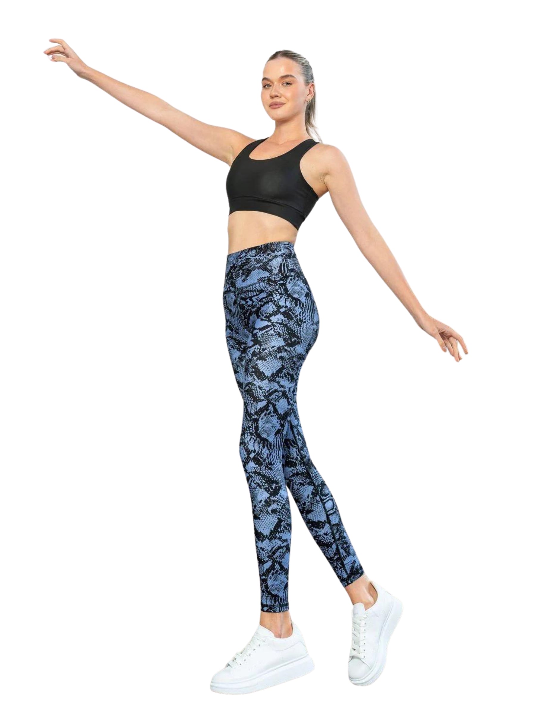 Frau posiert in Lismina 422 Extra High Waist Leggings, schwarzem Sport-BH und weißen Turnschuhen, die Arme ausgestreckt.