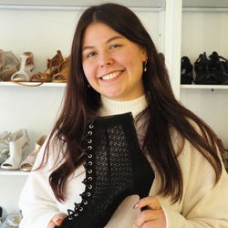 Lächelnde Frau hält einen schwarzen Schnürstiefel in einem Schuhgeschäft.