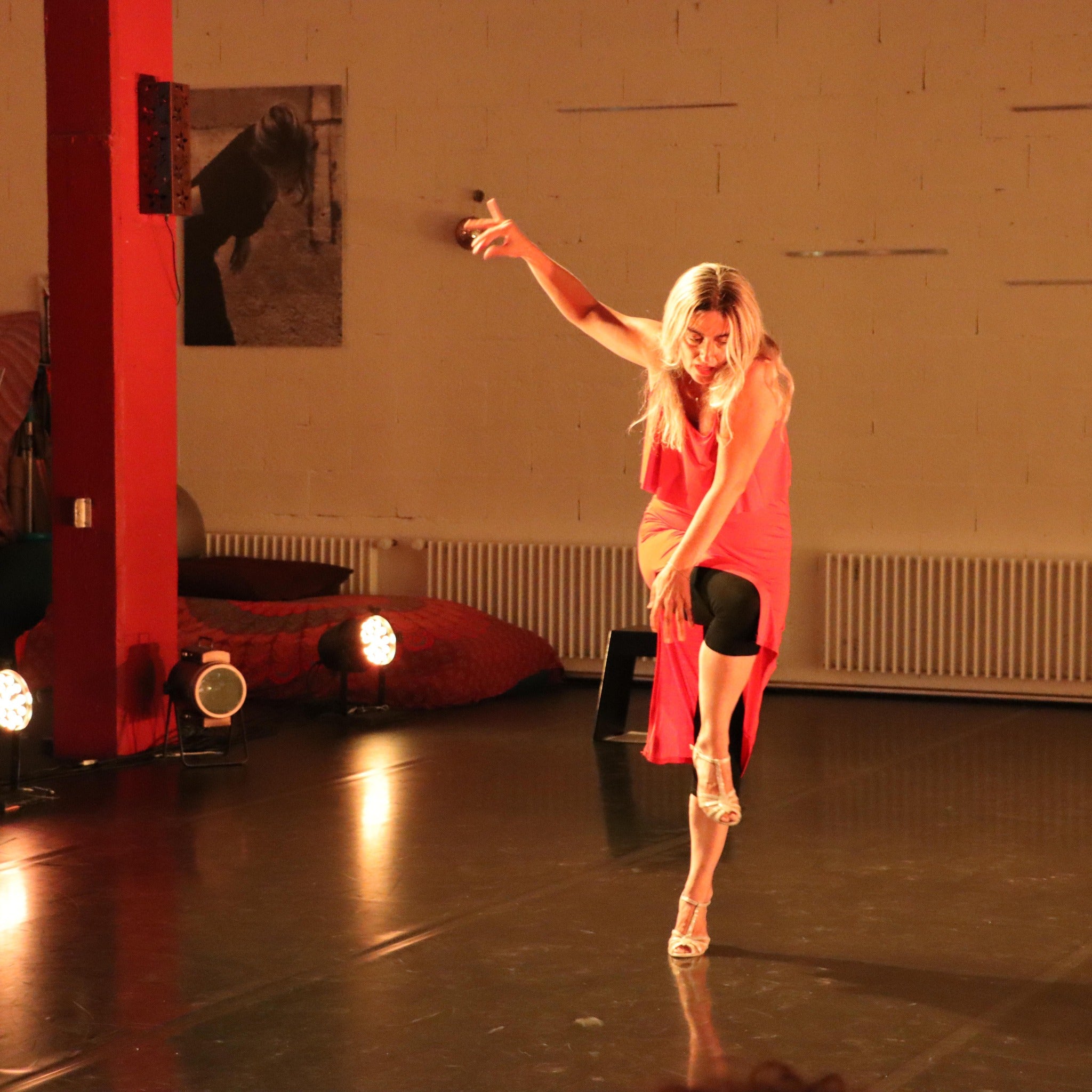 Sophie Z von Tanzkurse verkörpert künstlerischen Ausdruck, indem eine Frau anmutig auf einer schwach beleuchteten Bühne tanzt.