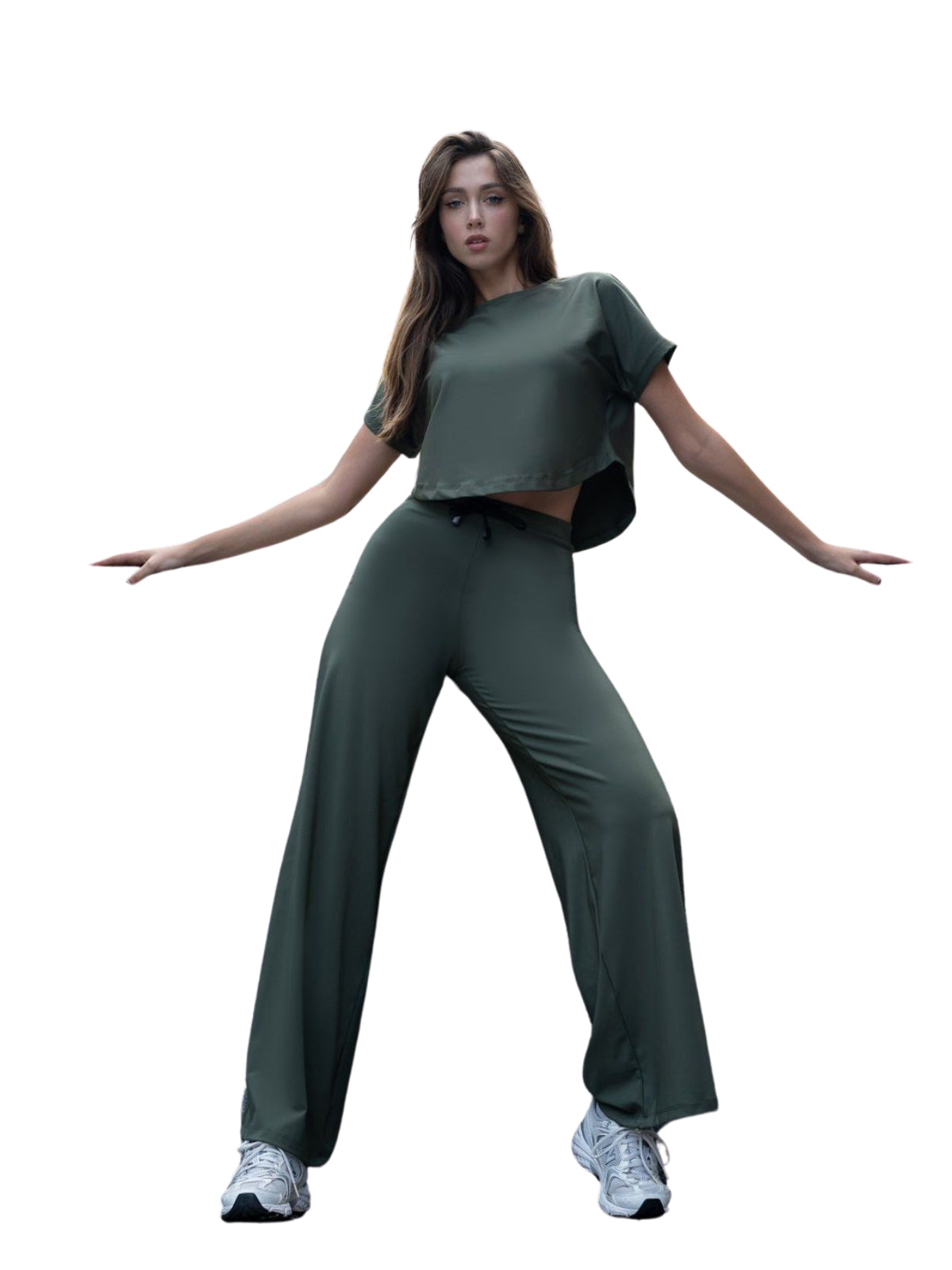 Posiert in einem grünen Outfit mit Schlaghose, Komfort-Sneakers und Lisminas 098 Yoga-T-Shirt in Khaki auf Weiß.