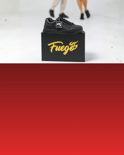 Ein schwarzer Turnschuh auf einer Schachtel mit der Aufschrift Fuego, im Hintergrund tanzen unscharfe Menschen.