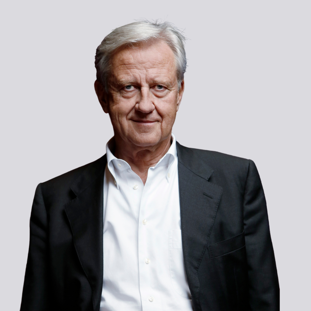 Älterer Mann in schwarzer Anzugsjacke und weißem Hemd vor einem schlichten hellen Hintergrund.