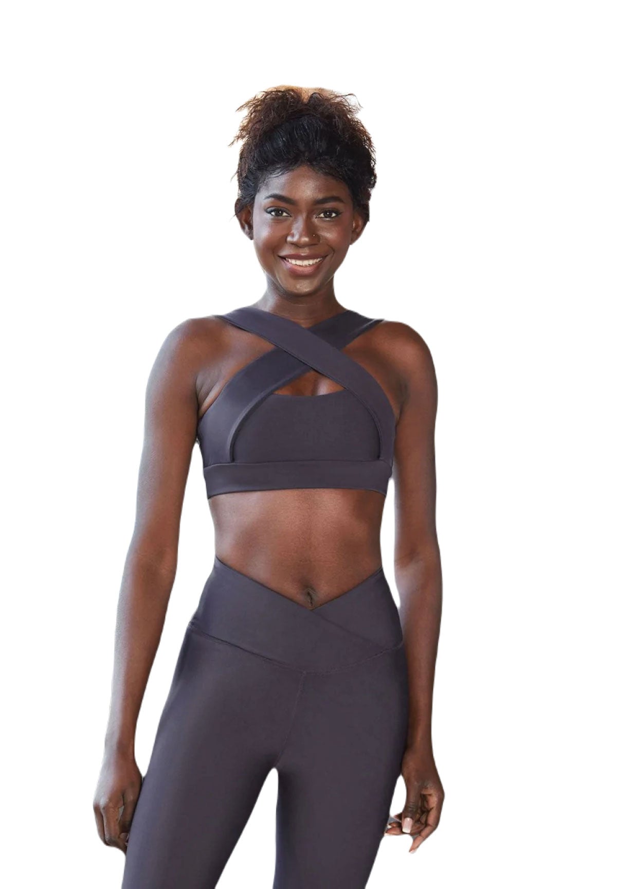 Lächelnde Person in Lisminas 206 Decoltée Sport-BH und Leggings, bereit für Yoga vor einem weißen Hintergrund.