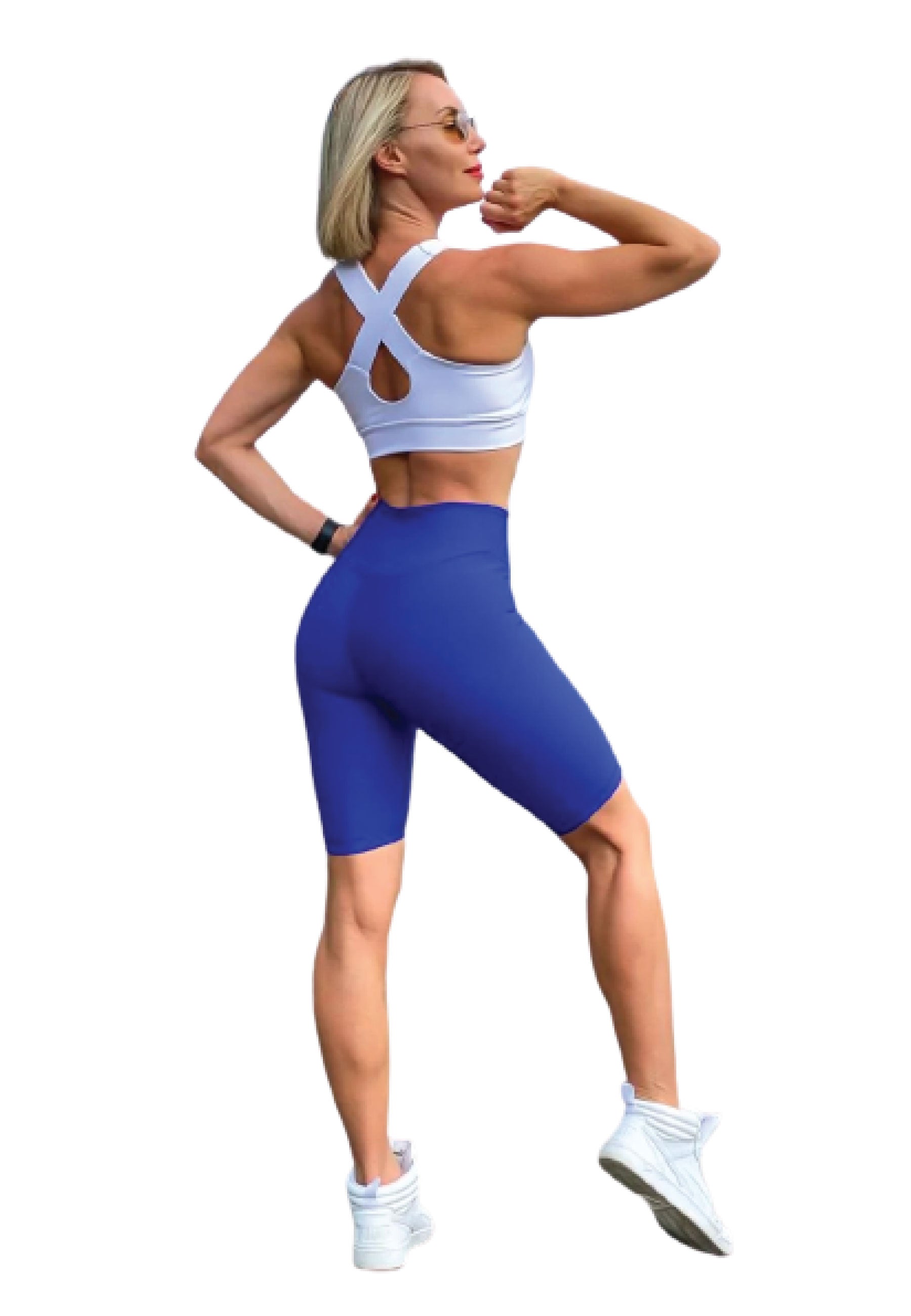 Frau in Trainingskleidung spannt den Arm an und trägt Lisminas 102 Single Crossed Sport-BH in Weiss, blaue Shorts und Turnschuhe.