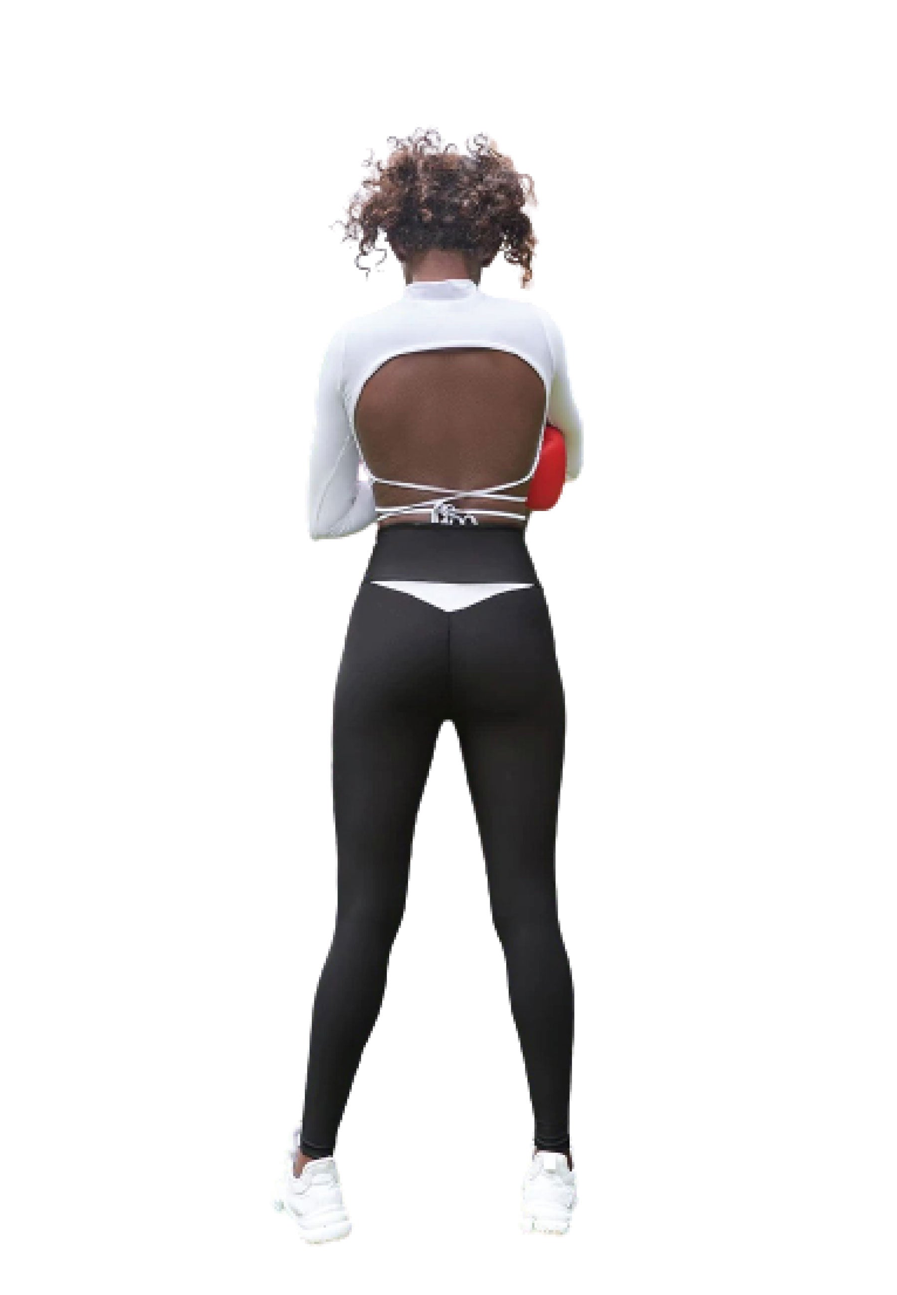 Lockenkopf im Sportoutfit und Sneakers, trägt ein Lismina 067 T-Shirt in Weiss und steht mit verschränkten Armen da.