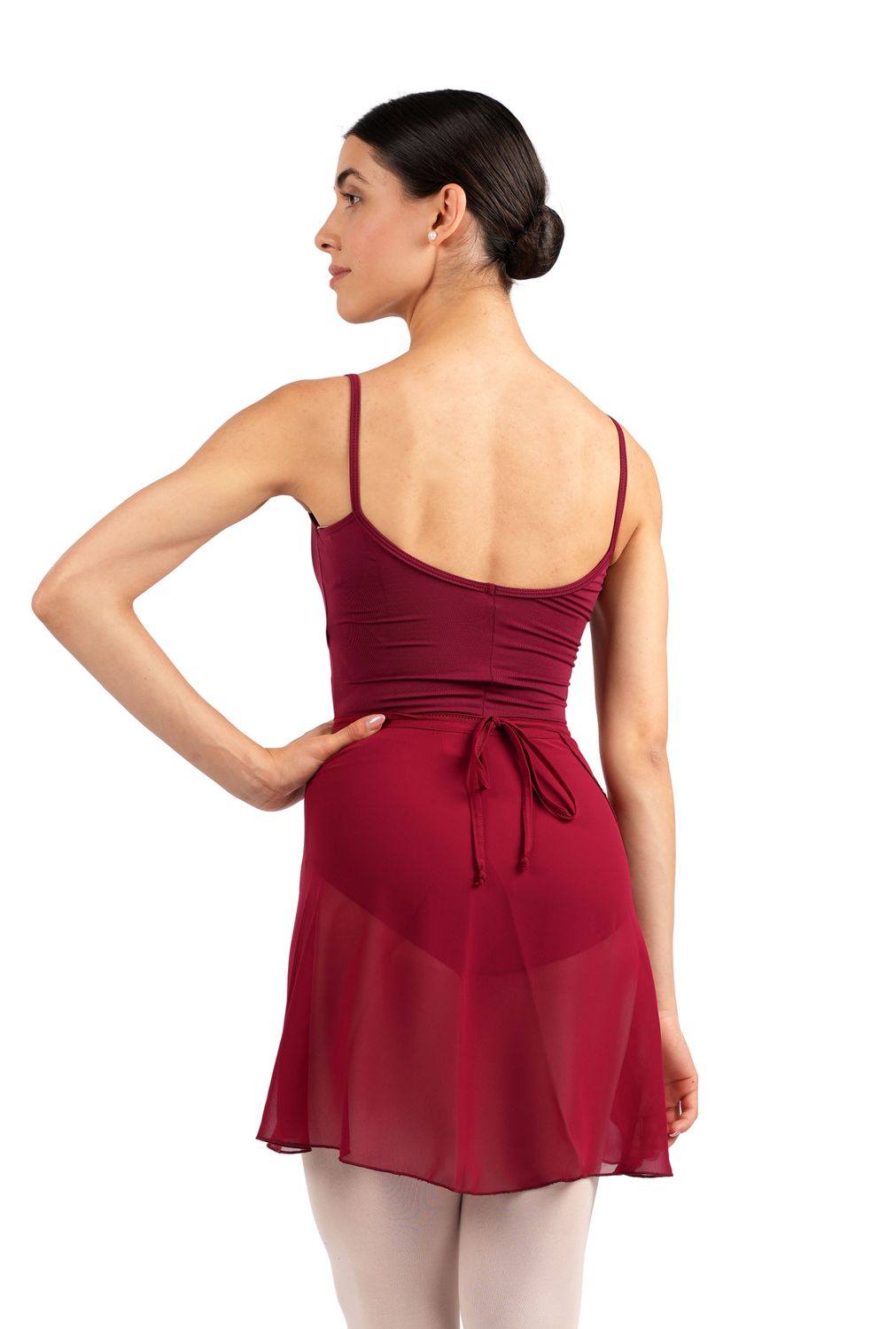 Eine Tänzerin in einem Rumpf R3050 Chiffon Wickelrock in Bordeaux, die mit einer Hand auf der Hüfte posiert, strahlt Eleganz aus.