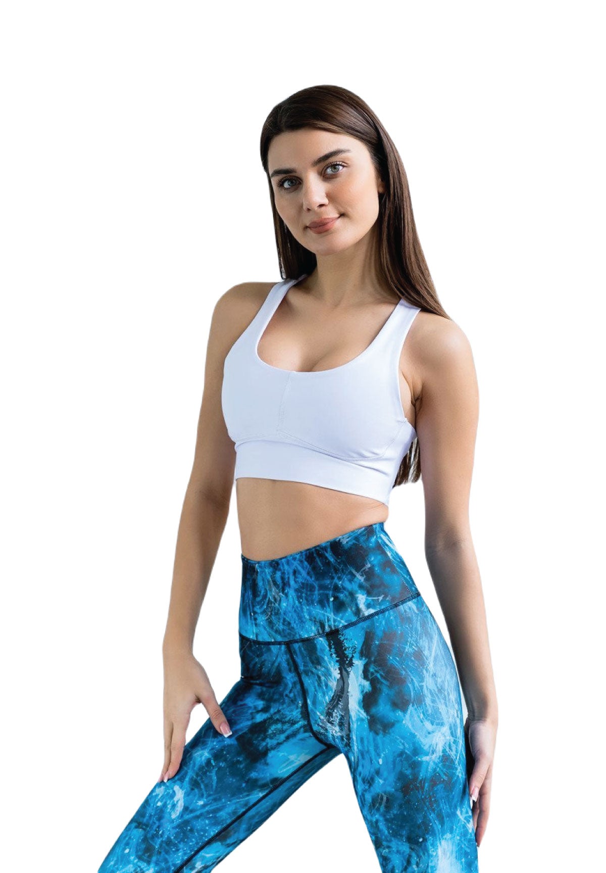 Frau in Lisminas 236 Fit Sport-BH in Weiss und blauen Leggings posiert selbstbewusst, Hand auf der Hüfte, auf Weiss.